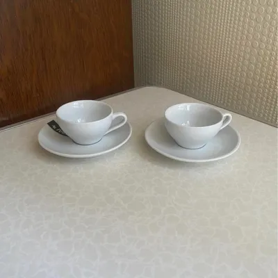 Lot de 2 tasses en céramique blanche avec leurs sous-tasses assorties.